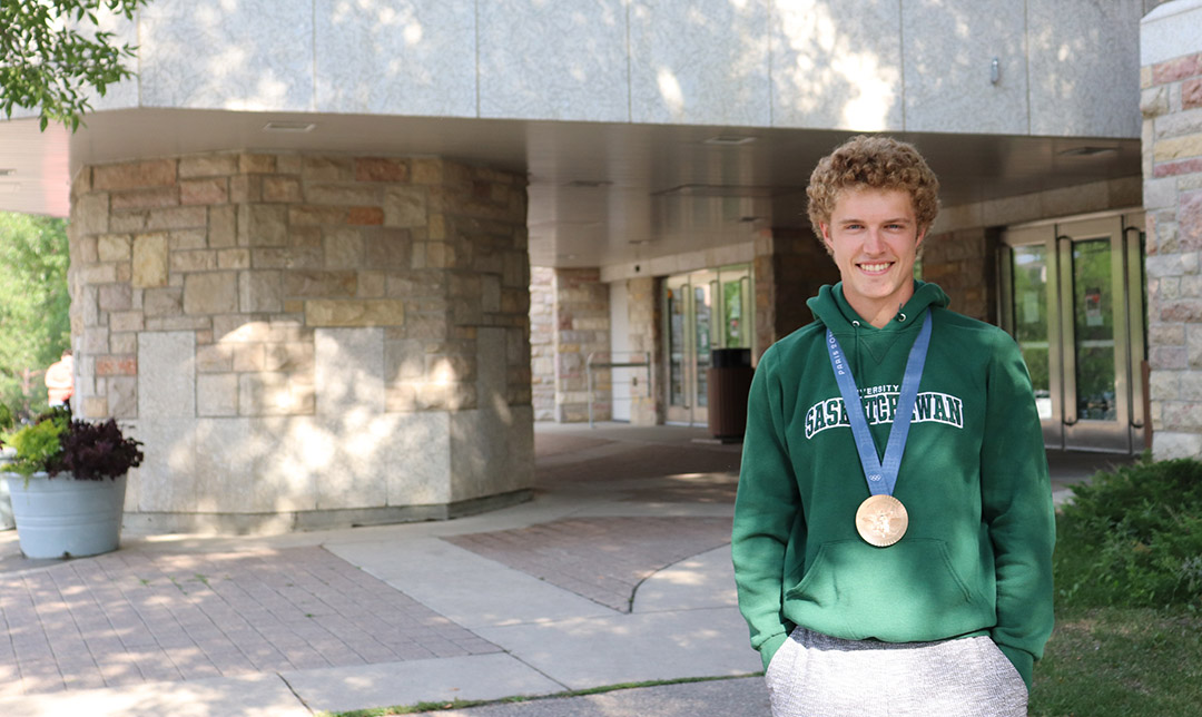 USask kinesiology student Rylan Wiens at the entrance to the Physical Activity Centre with his Olympic bronze medal from the Paris Summer Games. (Photo: Alyssa Wiebe)